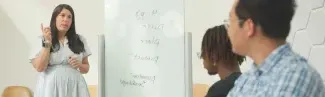 A professor talks to three students in a small classroom